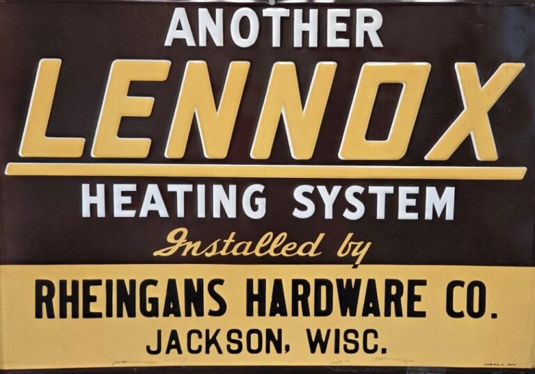 Vintage sign advertises Lennox Heating System, installed by Rheingans Hardware Co., Jackson, Wisconsin. Features bold typography on a brown and yellow background.