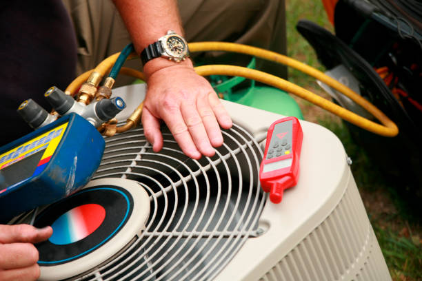 Technician's hand on an outdoor AC unit next to HVAC gauges